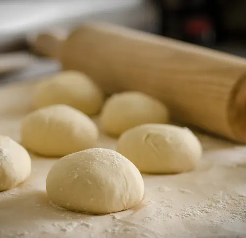 A soft looking dough with a rolling pin