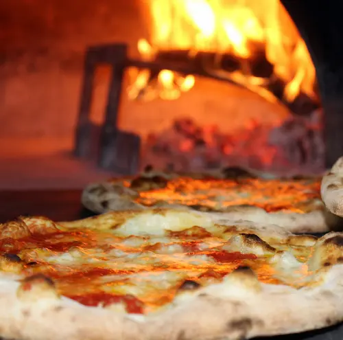 A pizza in front of the traditional oven